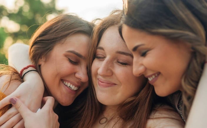 Photo of three women hugging and smiling together Photo of three women hugging and smiling together