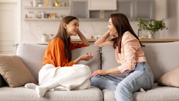 Mother and teenaged daughter talking on couch Mother and teenaged daughter talking on couch