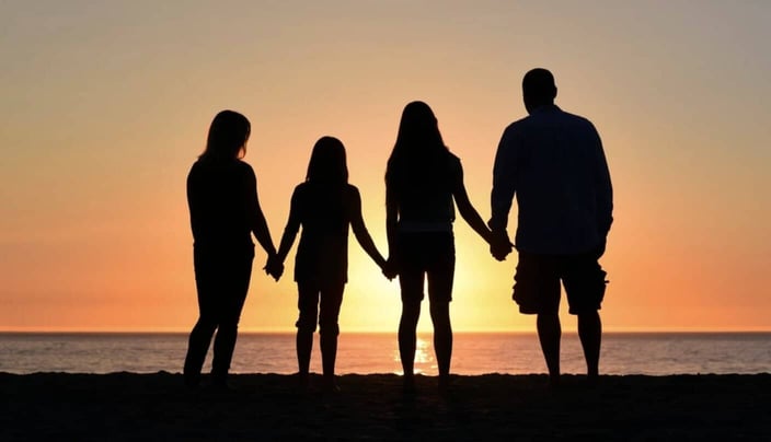 Photo silhouettes of a father, mother, and two kids holding hands and standing together looking out at the ocean Photo silhouettes of a father, mother, and two kids holding hands and standing together looking out at the ocean
