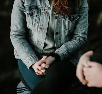 Photo of a woman sitting seriously with her hands clasped Photo of a woman sitting seriously with her hands clasped
