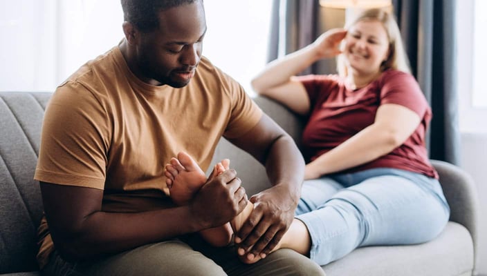 Photo of a happy young man massaging a happy young woman's feet on a couch Photo of a happy young man massaging a happy young woman's feet on a couch
