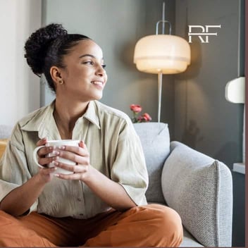 Photo from Retreat Finder of a woman holding a mug and looking out the window while smiling and looking peaceful