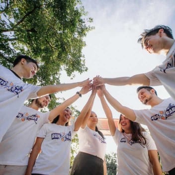 Photo of a group of young people wearing matching shirts and doing a group high-five