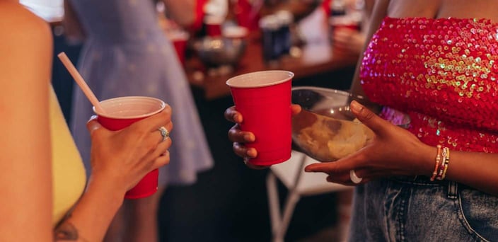 Two women talking at a party, holding red solo cups