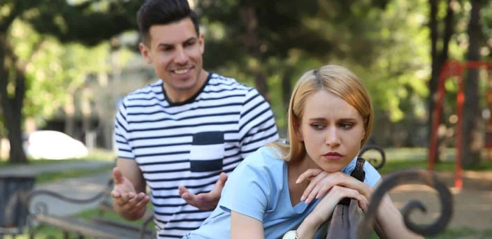 Woman looking annoyed as man talks to her.