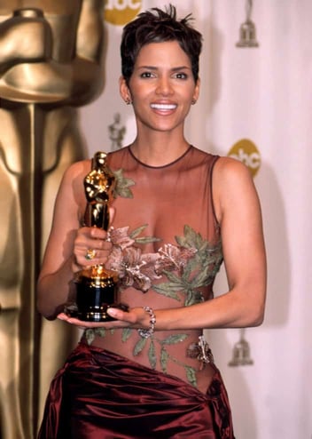 Halle Berry holding up her Oscar award in 2002 while wearing her famous Elie Saab gown