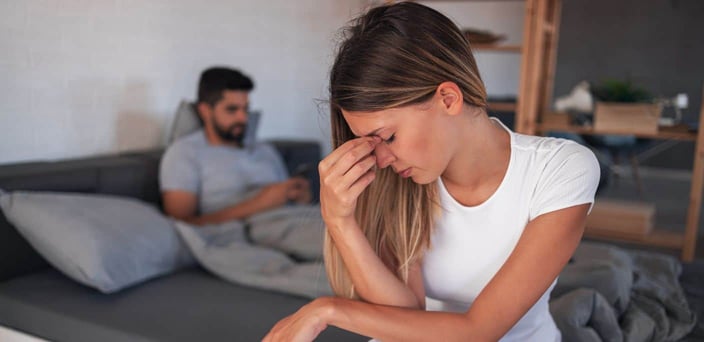 Man on phone while woman looks exhausted in the foreground. Man on phone while woman looks exhausted in the foreground.