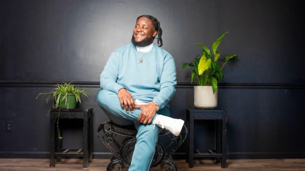 Moe Ari Brown, Hinge's Love & Connection Expert and co-author of the dating app's LGBTQIA+ D.A.T.E. Report, seated and smiling during a portrait session.