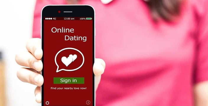 Photo of woman holding phone that says online dating sign in Photo of woman holding phone that says online dating sign in
